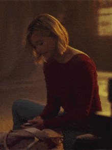 a woman in a red shirt sits on the floor
