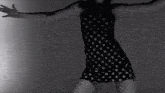 a woman in a black and white polka dot dress is adjusting her skirt .