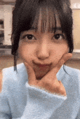 the girl is wearing a blue sweater and making a face with her hand .