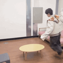 a man in a white jacket is running towards a yellow table