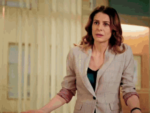 a woman in a plaid jacket stands in front of a wall