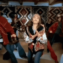 a man with long hair and a mustache is dancing with a group of people in a room .