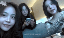 three girls are posing for a picture and one of them is holding a phone