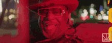 a man wearing a red hat and sunglasses is smiling in a car .