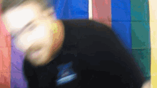 a blurry picture of a man standing in front of a colorful flag