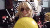a blonde woman wearing sunglasses is holding a yellow ball