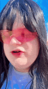 a little girl wearing pink sunglasses and a blue shirt .