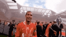 a man in a red shirt is standing in a stadium with a trophy .