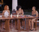 three women are sitting at a table with food and candles .