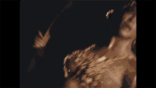a close up of a woman in a gold dress dancing in the dark .