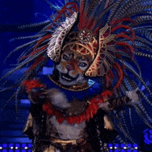 a cat is wearing a feathered headdress and dancing on a stage .