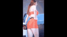 a woman in a red bikini top and red skirt is standing in front of a car .
