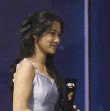 a woman in a blue dress holding a trophy that says asia