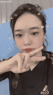 a woman wearing a black adidas shirt shows a peace sign