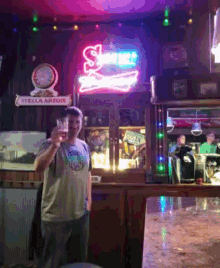 a man stands in front of a sign that says stella artois on it