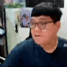a man wearing glasses is making a funny face while sitting at a desk .