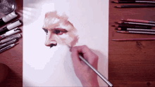 a person is drawing a portrait of a man 's face with a pencil