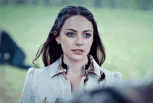a woman with blue eyes is wearing a white jacket and a choker