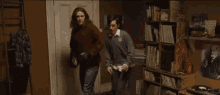 a couple of people are dancing in a room with a bookshelf .