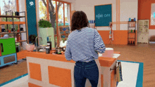 a woman in a striped shirt is standing in front of a sign that says bake off