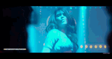 a woman is dancing in a club with blue lights behind her .