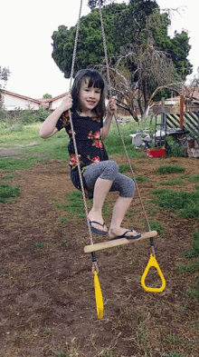 a young girl is sitting on a swing with a yellow ring attached to it