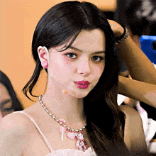 a close up of a woman wearing a pink dress and a necklace