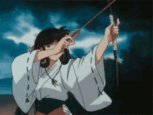 a woman in a kimono is holding a bow and arrow in her hand .