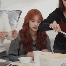 a woman with red hair is sitting at a table with bowls