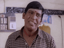 a man in a plaid shirt is smiling and looking at the camera