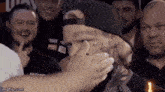 a man with a tattoo on his forehead is being touched by a group of people .