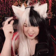a woman wearing a black and white cat ear headband is smiling
