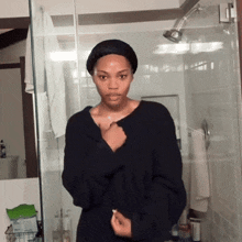 a woman in a black sweater stands in front of a glass shower door