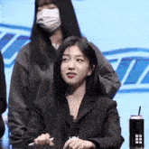 a woman wearing a mask holds a pen in her right hand