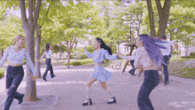 a group of girls are dancing in a park with trees in the background