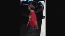 a child in a red shirt is standing in a doorway