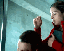 a woman in a red jacket is holding a man 's head