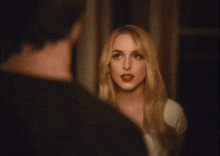 a woman with red lipstick looks at a man in a black shirt