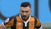 a man with a beard is wearing an umbro shirt