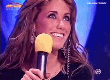 a woman is smiling while holding a microphone in front of a sign that says anapioverdose