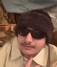 a man wearing sunglasses and a beanie is making a funny face