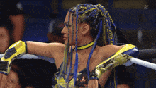 a woman with blue and yellow braids is standing in a boxing ring