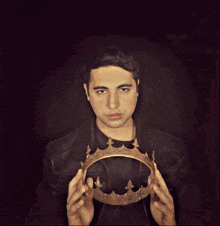 a man in a leather jacket is holding a gold crown over his head