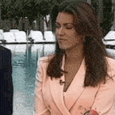 a woman in a pink jacket is sitting next to a pool .