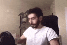 a man with a beard is sitting in a chair in a room with his eyes closed .
