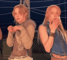two women are standing next to each other and one of them is covering her mouth with her hand