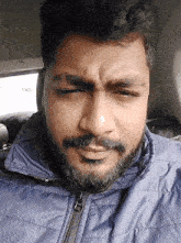a man with a beard wears a blue jacket with a zipper