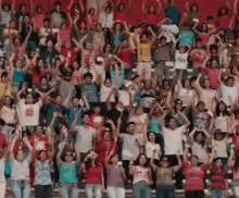 a crowd of people are raising their arms in the air in a stadium