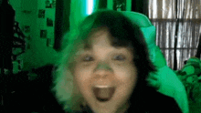 a young girl is making a funny face in front of a green background .