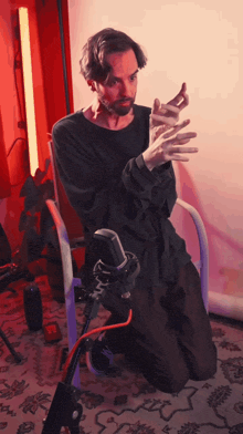 a man is kneeling down in front of a microphone with his hands in the air